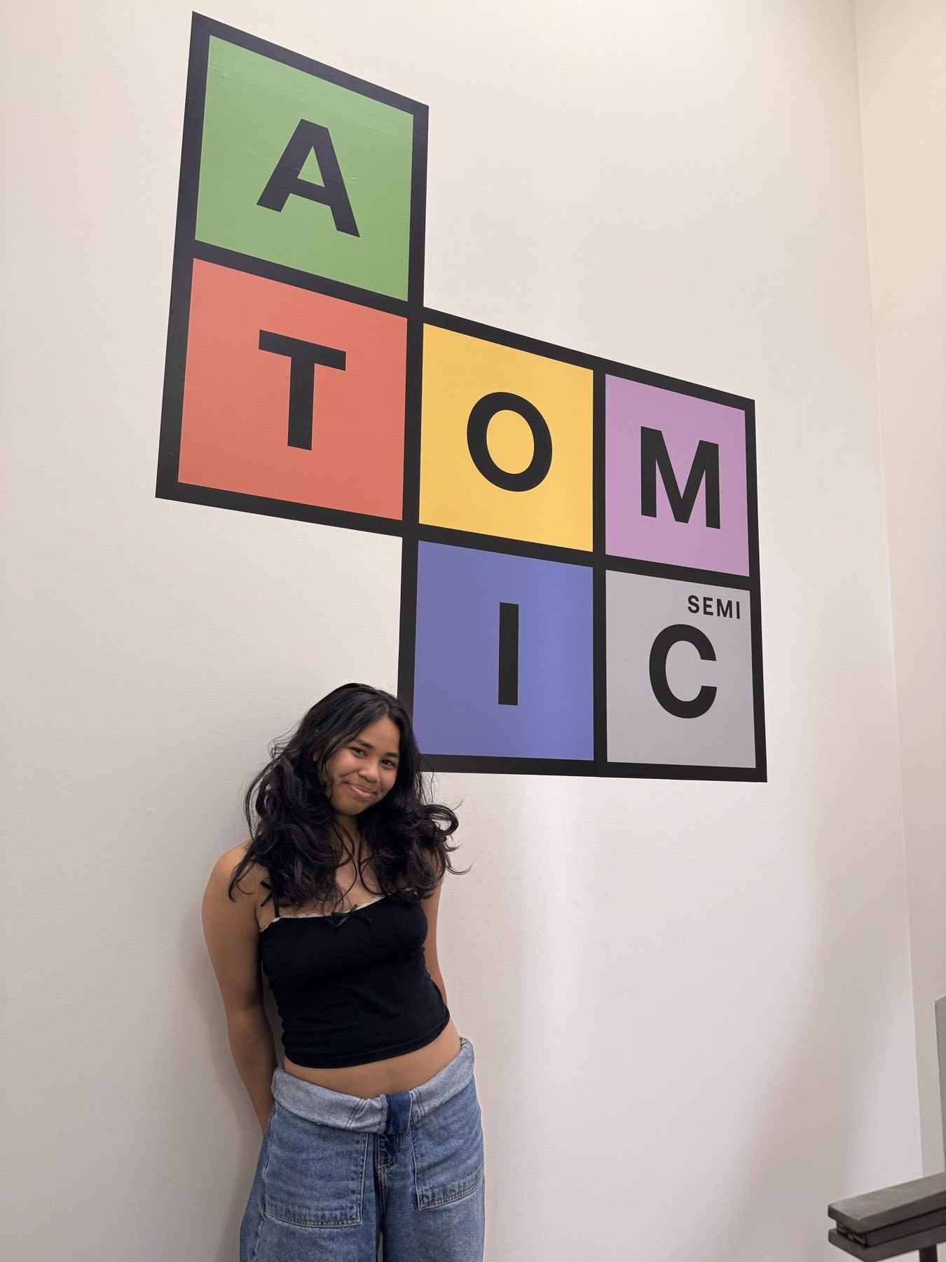 Inez at the Atomic Semi office wall logo